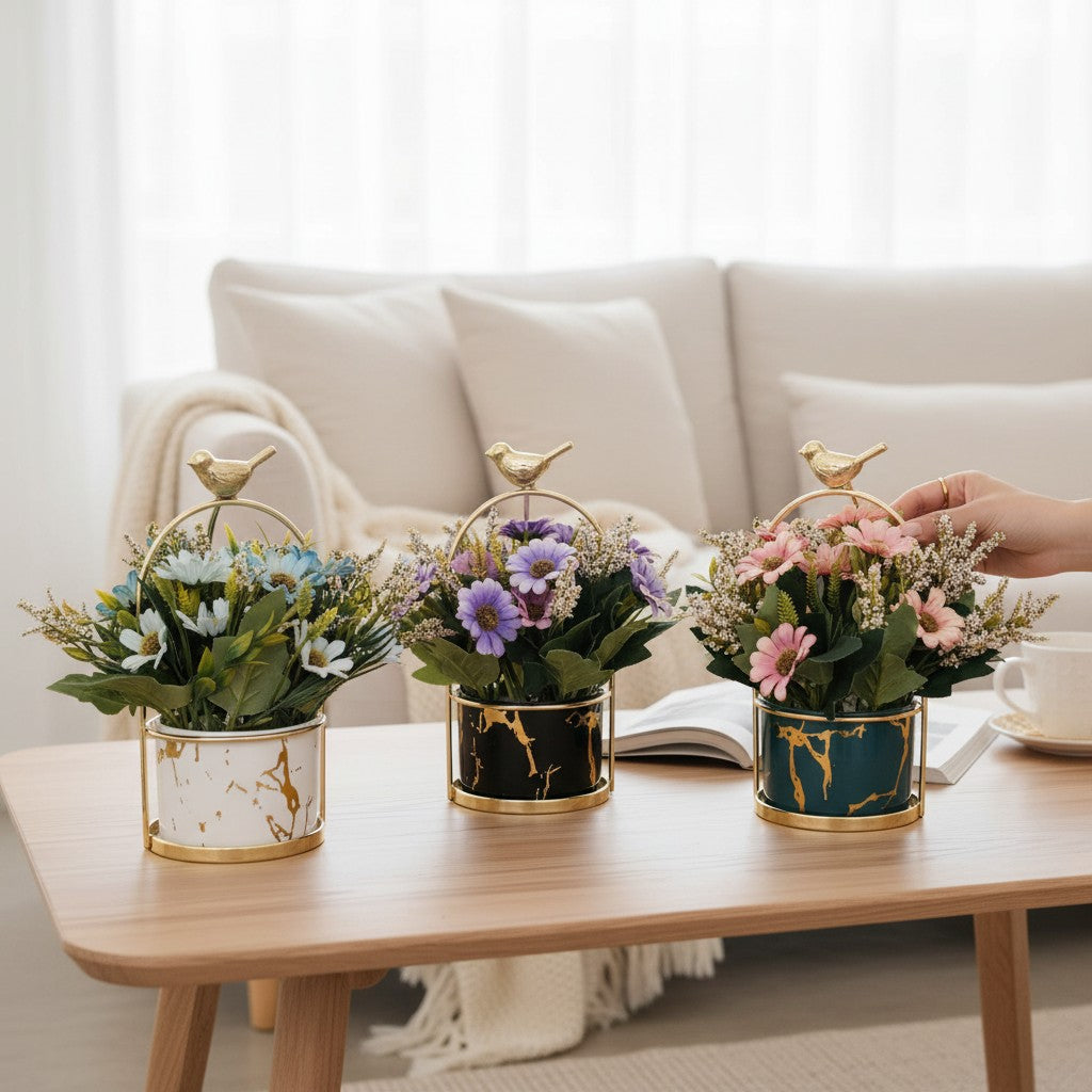 Home Sajawat artificial flower pots with marble-effect ceramic, gold bird accents, and colorful faux floral arrangements.