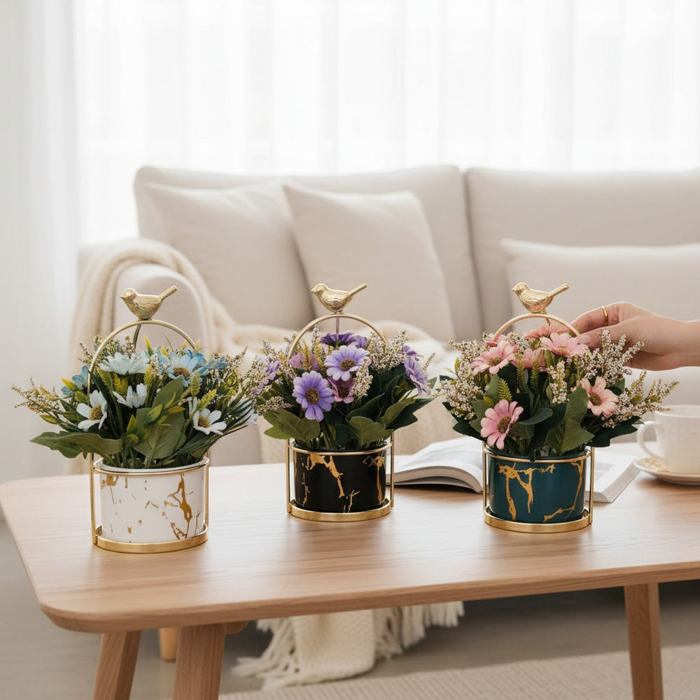 Home Sajawat artificial flower pots with marble-effect ceramic, gold bird accents, and colorful faux floral arrangements.