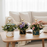 Home Sajawat artificial flower pots with marble-effect ceramic, gold bird accents, and colorful faux floral arrangements.