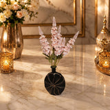 Home Sajawat matte black circular vase with carved details holding a bouquet of soft pink faux floral stems