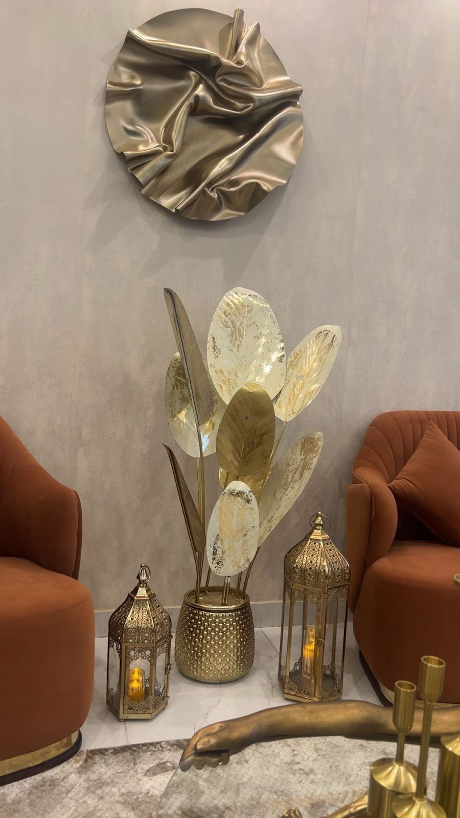 Home Sajawat decorative metal leaf floor sculpture in gold and white with a textured cylindrical base in a living room