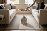 Home Sajawat metallic side table with a circular top and laser-cut bell-shaped base in a modern living room setting.