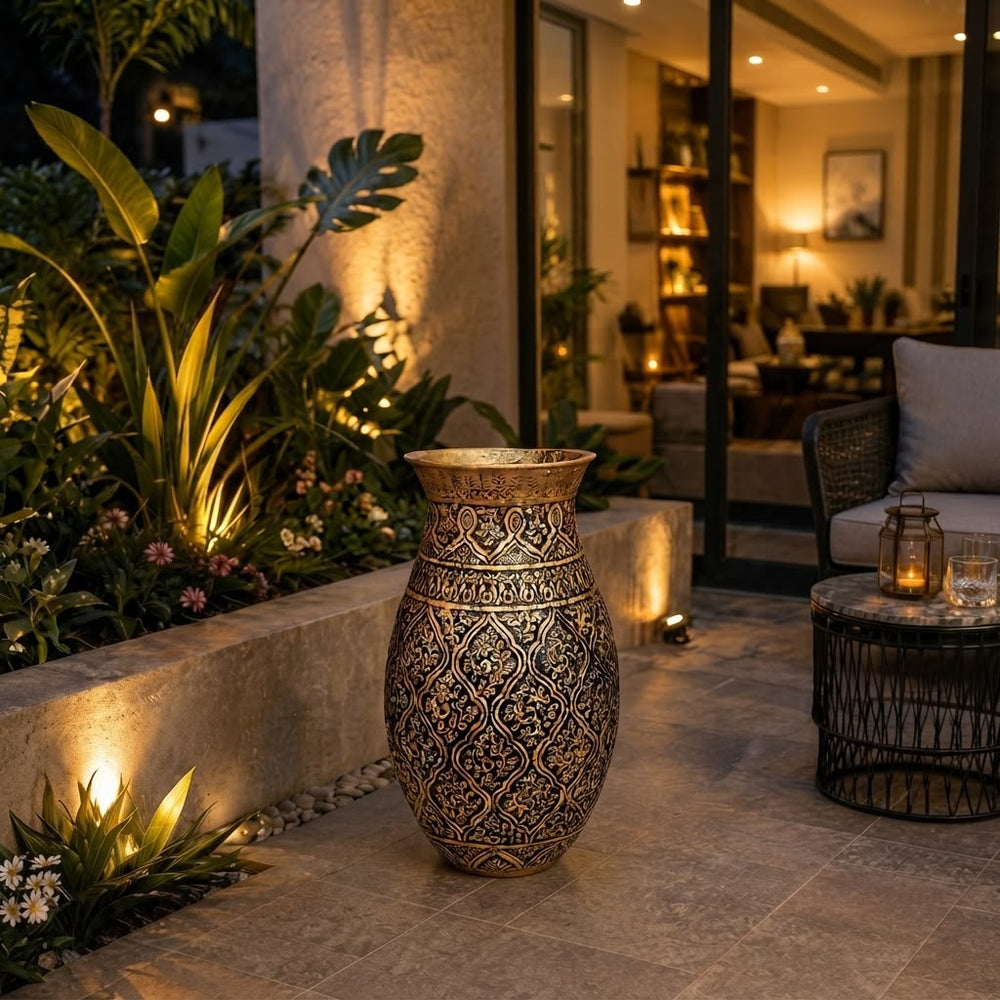 Home Sajawat ornate metallic floor vase with embossed patterns on a patio at night with warm ambient lighting.