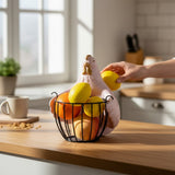 Home Sajawat pink chicken-shaped fruit basket with metal wire base holding fresh citrus on a kitchen countertop