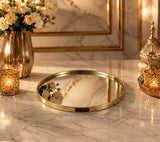 Home Sajawat round gold metal mirror serving tray with HOME branding on a marble table with candles and flowers
