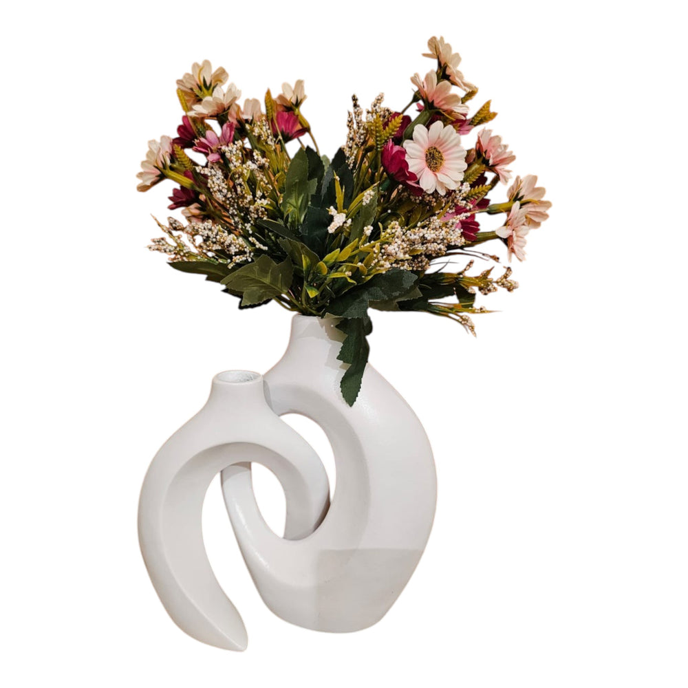 Home Sajawat white ceramic abstract hollow-center vase with a bouquet of colorful faux flowers on a wooden table