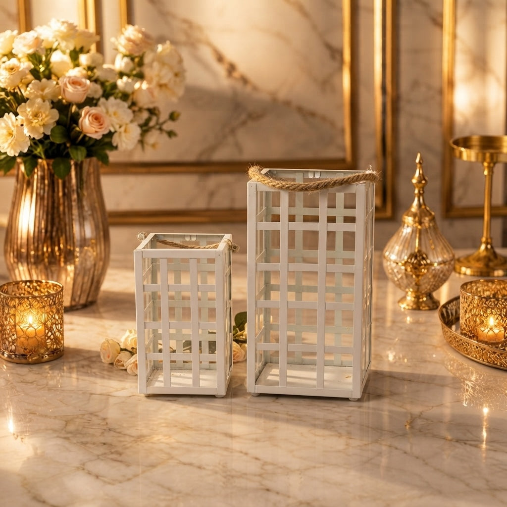 Home Sajawat set of two white metal lanterns with lattice design and rustic rope handles on a marble table.