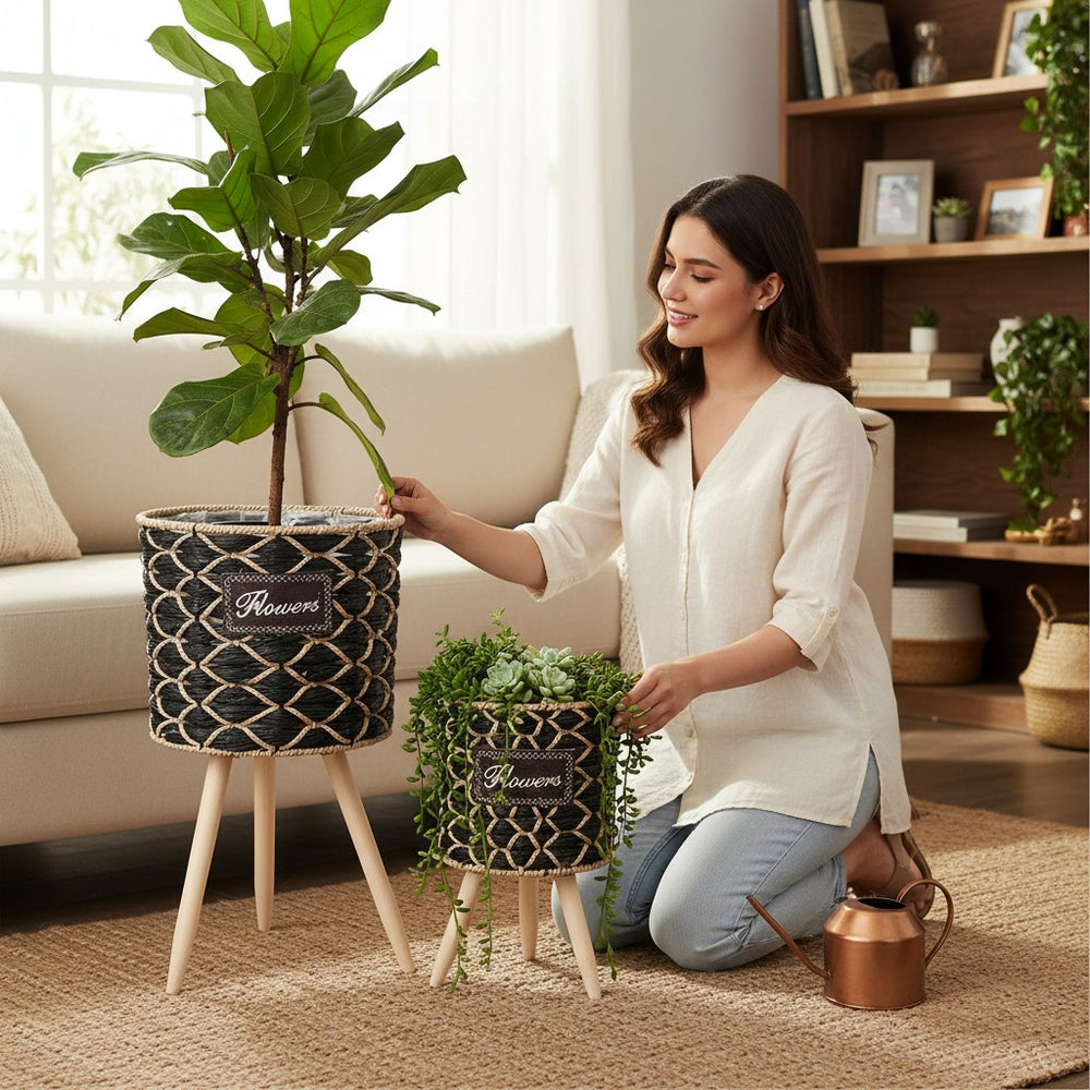 Home Sajawat set of 2 black and natural woven raffia planters with wooden legs and "Flowers" patch.