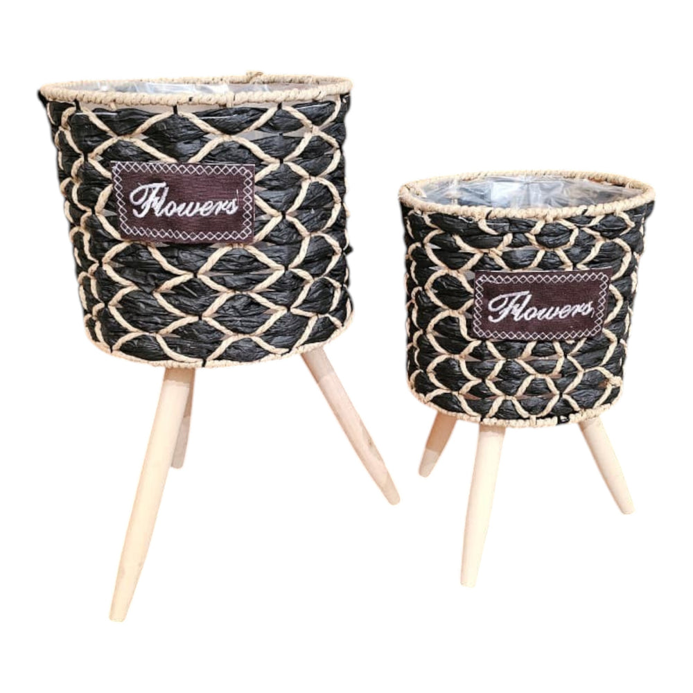 Home Sajawat set of 2 black and natural woven raffia planters with wooden legs and "Flowers" patch.
